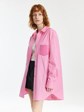 A lady wears an oversized pink shirt.